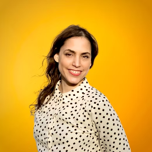 Sabina D'Ercole smiling against a warm yellow background